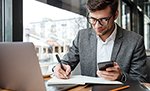 Smiling business man in eyeglasses sitting by table in cafe